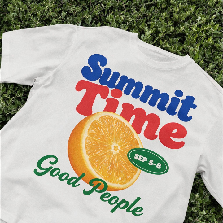 Sırtında renkli "Summit Time" baskısı bulunan beyaz kurumsal tişört, çim üzerinde