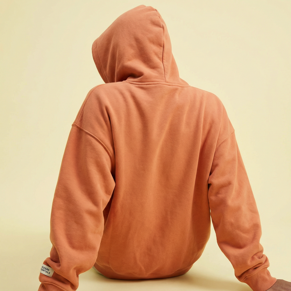 Turuncu oversize kurumsal hoodie giyen kişi, arkadan görünüm